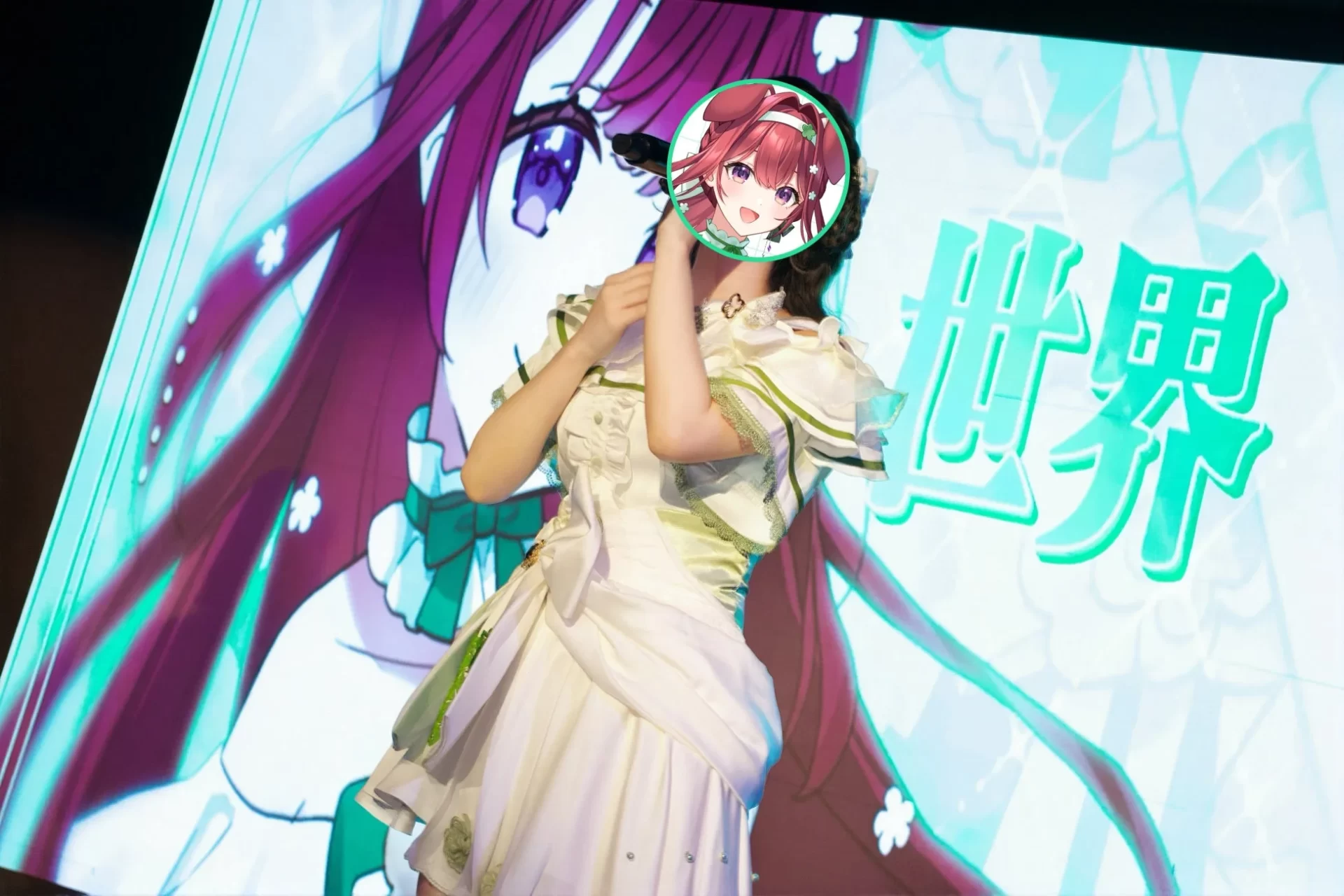 白いドレスを着た女性がステージ上でパフォーマンスを行っており、背景には大きなスクリーンにアニメキャラクターと「世界」の文字が映し出されている