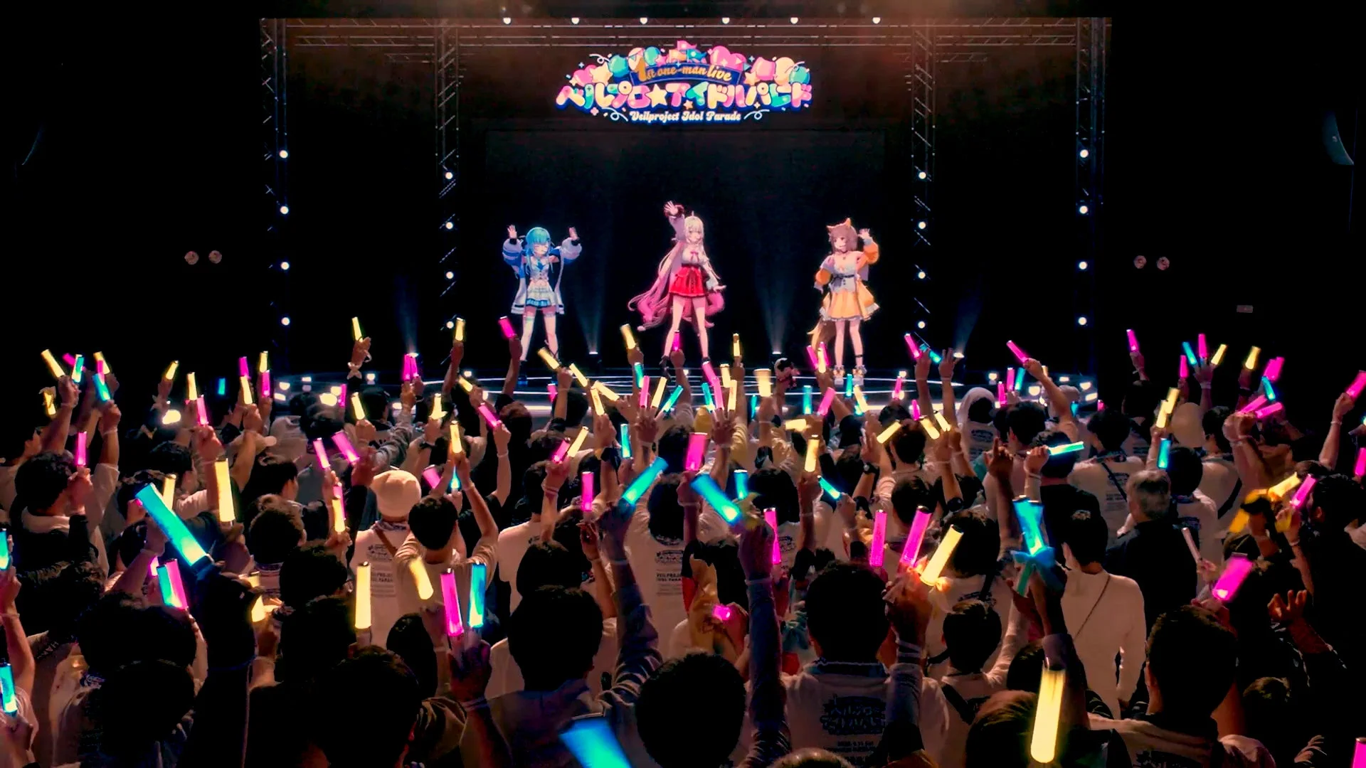 ステージでパフォーマンスするバーチャルアイドルとペンライトを振る多くの観客